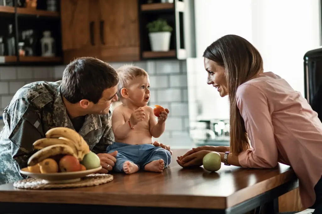 Familia acompañando a su bebé mientras prueba fruta en casa.
