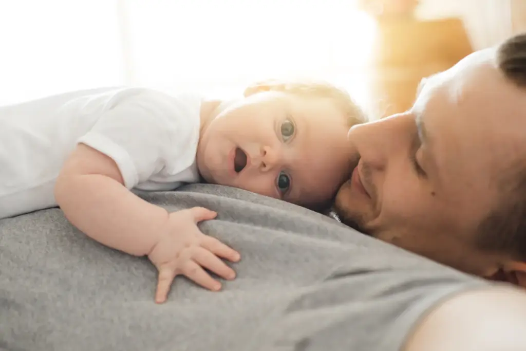 Padre descansando con su bebé recostado sobre el pecho.