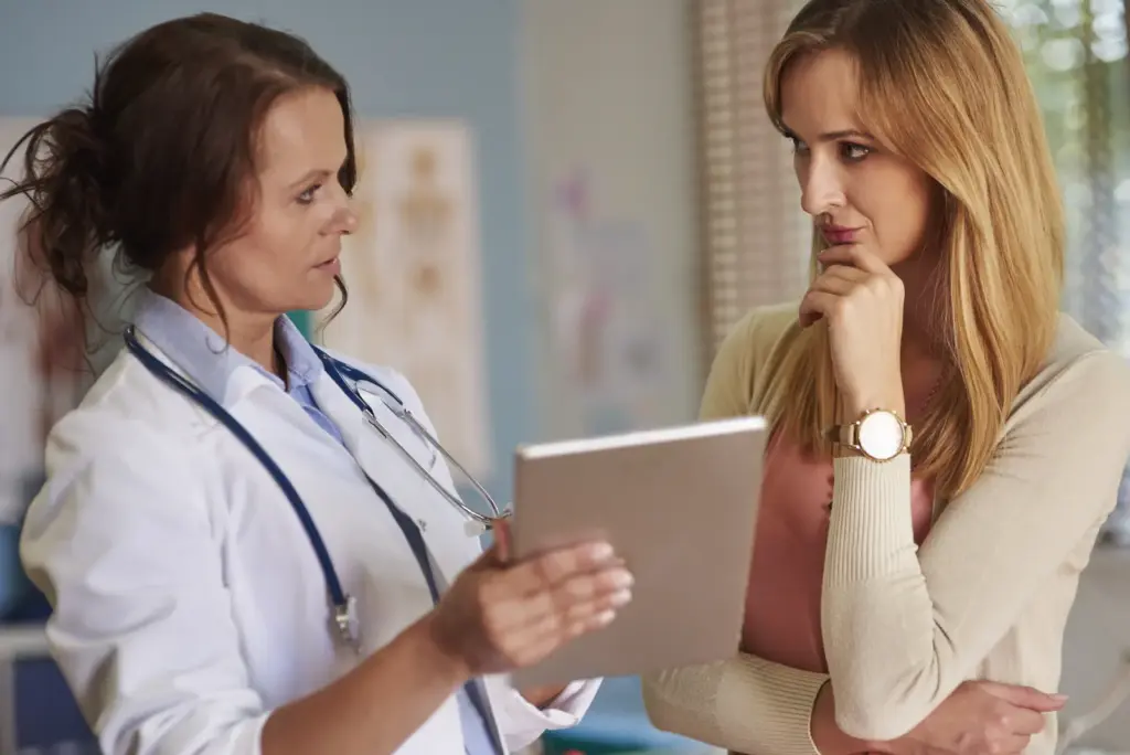 Profesional sanitaria escucha a una mujer durante una consulta.