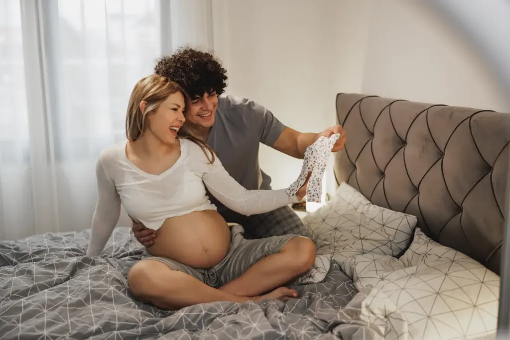 Pareja embarazada preparando ropa para la llegada de su bebé.